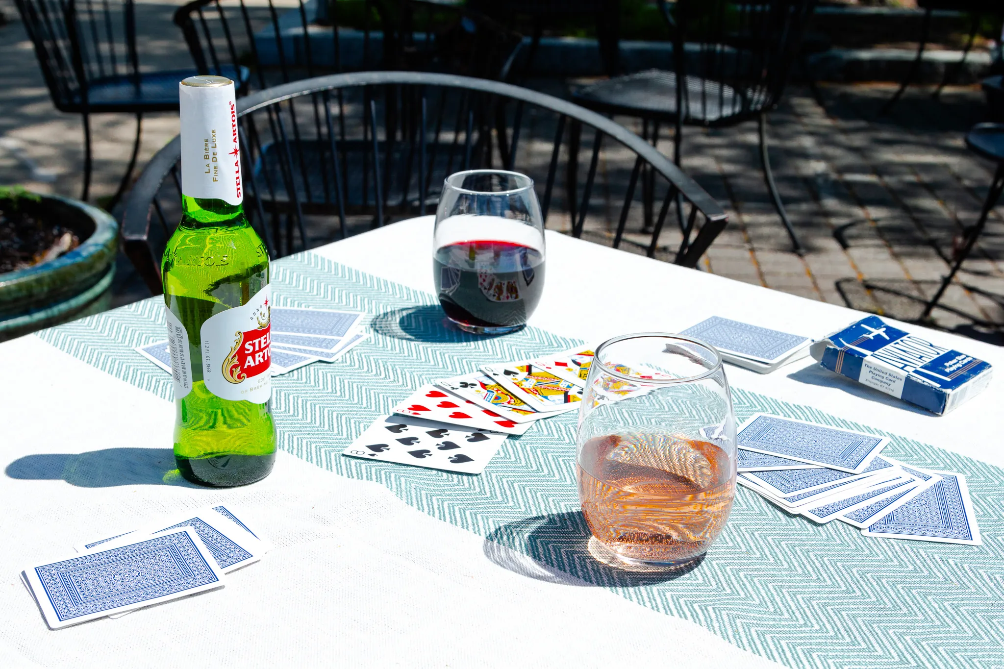 Beer, rosé and red wine among playing cards on the patio
