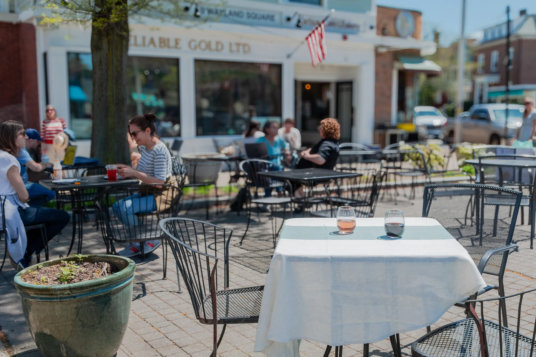 Guests at tables on the L’Artisan patio in Wayland Square on a sunny day